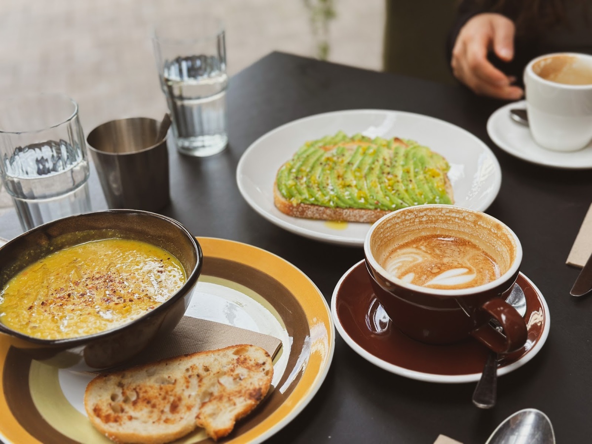 Food spread at Kopi Cafe with dhal, toast, avocado toast, and coffee.